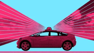 Autonomous vehicle with rooftop sensor emitting pink laser beams against a bright blue sky.