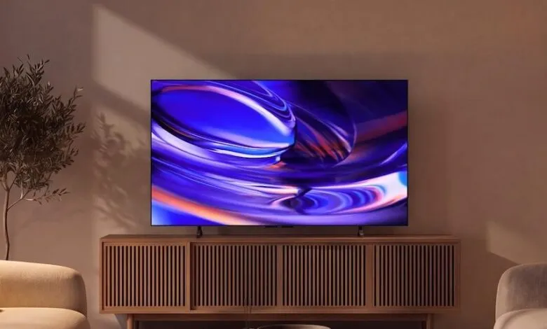 A sleek Sony Bravia TV mounted on a wooden media console displaying a vibrant abstract blue graphic.
