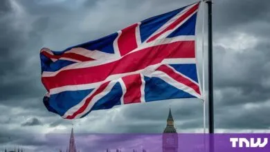 Union Jack flag waving proudly against a dramatic, stormy sky in London.