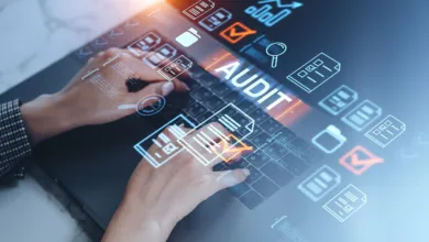 Hands typing on a laptop with glowing audit and document icons overlaid.