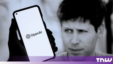 Gary Marcus looking intently at a smartphone displaying the OpenAI logo
