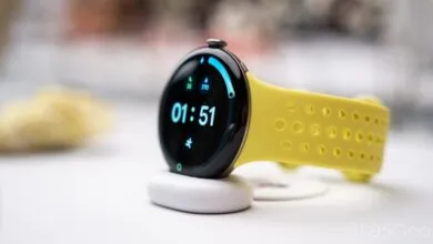 Google Pixel Watch with a vibrant yellow perforated active band sitting on a charging puck.