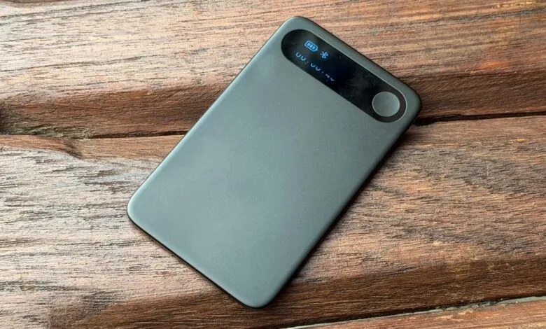 Black portable power bank rests diagonally on a rustic dark wooden surface.