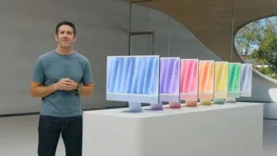 John Ternus presenting M4 iMacs in various vibrant colors on a white display table.