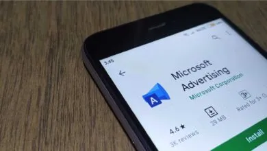 Smartphone displaying the Microsoft Advertising app page in an app store on a wooden surface.