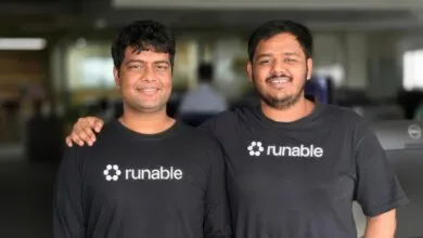 Runable co-founders Umesh and Saksham smiling together in matching black t-shirts.