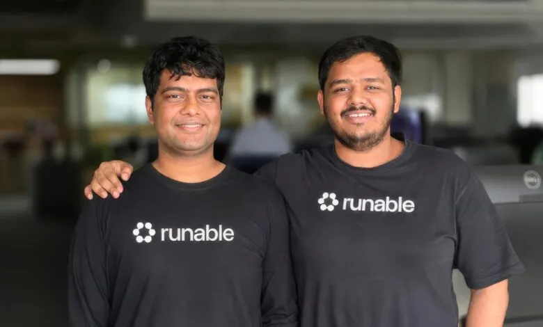 Runable co-founders Umesh and Saksham smiling together in matching black t-shirts.