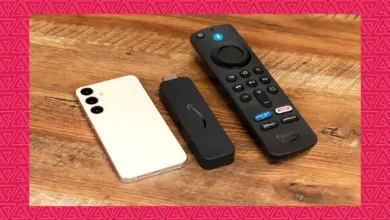 Samsung Galaxy phone next to an Amazon Fire TV stick and remote on wood