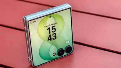 Folded silver smartphone with green cover screen resting on red wooden surface