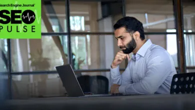 Professional working attentively on a laptop in a modern office with large windows.