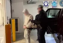 Law enforcement officers arresting a suspect in a hooded sweatshirt inside a parking garage