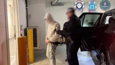 Law enforcement officers arresting a suspect in a hooded sweatshirt inside a parking garage