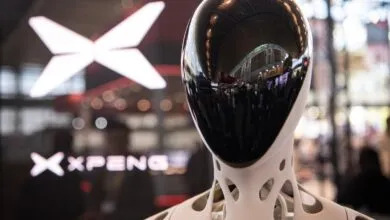 Close-up of an XPeng humanoid robot head with a glossy black faceplate and white skeletal neck.