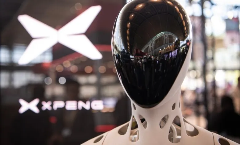 Close-up of an XPeng humanoid robot head with a glossy black faceplate and white skeletal neck.