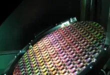 Close-up of a circular silicon semiconductor wafer with multicolored microchip dies.