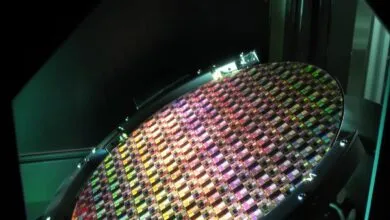 Close-up of a circular silicon semiconductor wafer with multicolored microchip dies.