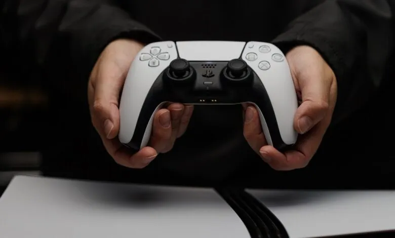 Close-up of hands holding a white and black PlayStation 5 DualSense controller.