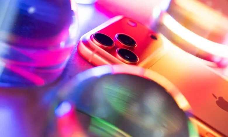 Close-up of an iPhone 17 Pro Max surrounded by glowing abstract lights and glass spheres.