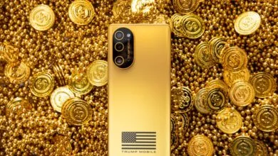 A gold-colored Trump Mobile smartphone resting on a background of gold coins and beads.