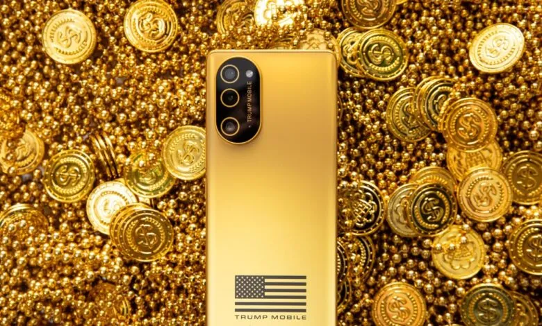A gold-colored Trump Mobile smartphone resting on a background of gold coins and beads.