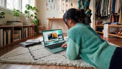 Woman in green sweater lying on a rug, working on a velvet green Dell laptop in her studio.