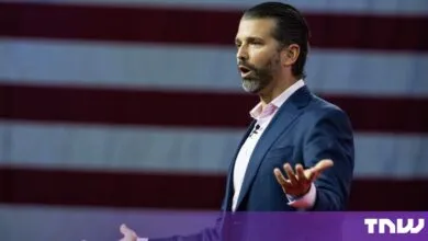 Donald Trump Jr. speaking passionately with gestures in front of an American flag.