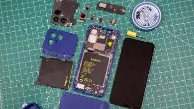 Disassembled modular Fairphone with internal components spread across a green cutting mat.