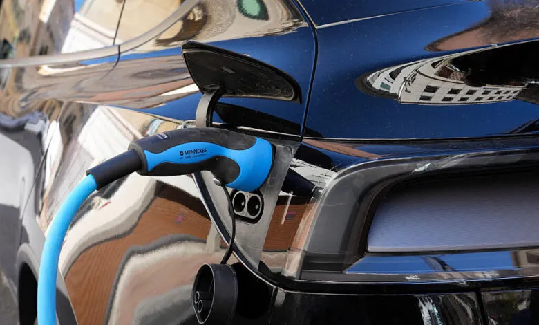Close-up of a blue Mennekes charging cable plugged into a black electric vehicle in Perpignan.