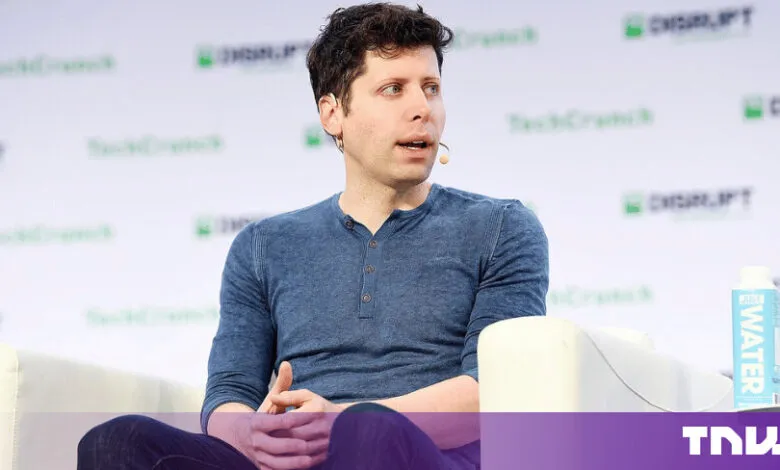 Sam Altman speaks on stage at a TechCrunch event wearing a blue shirt.