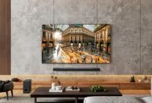 LG OLED TV mounted on a textured concrete wall displaying a vibrant Italian shopping arcade scene