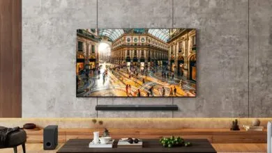 LG OLED TV mounted on a textured concrete wall displaying a vibrant Italian shopping arcade scene