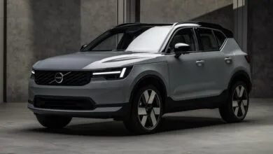 Silver Volvo XC40 compact SUV parked in a modern, moody concrete studio with dramatic lighting.