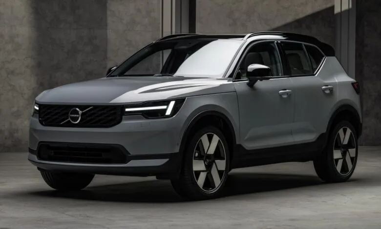 Silver Volvo XC40 compact SUV parked in a modern, moody concrete studio with dramatic lighting.