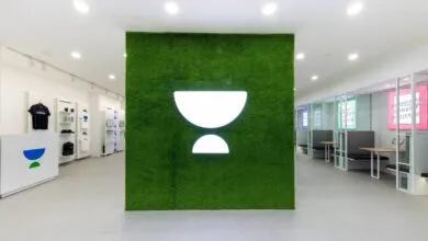Modern Unacademy office interior with a lit green grass accent wall featuring the company logo.