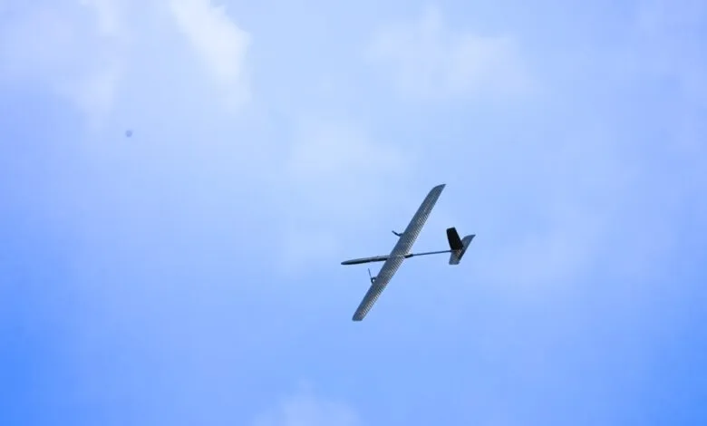 A sleek model airplane soaring gracefully through a bright blue sky with soft white clouds.