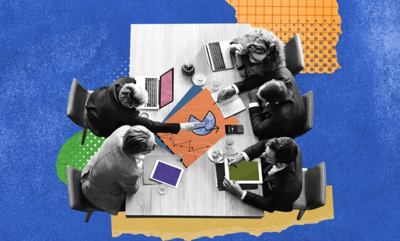 Overhead view of five people collaborating around a wooden meeting table with charts and laptops.