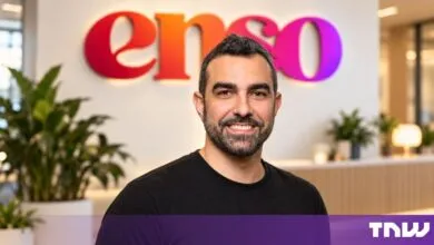 Amir Rajan, founder of enso, smiling in front of the colorful company logo in a modern office.