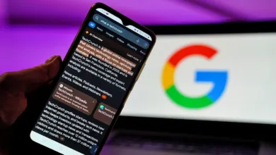 Smartphone displaying Google AI Overviews search results in front of a laptop showing the Google logo.