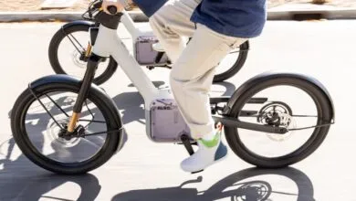 A person riding a modern white electric bicycle on a paved path outdoors.