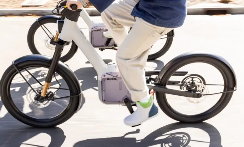 A person riding a modern white electric bicycle on a paved path outdoors.