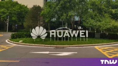 Large white Huawei logo sign installed on a grassy roundabout outside a modern research facility