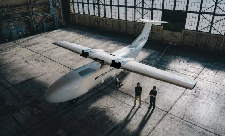 High-angle view of the Poseidon Aero Egret experimental aircraft inside a hangar with two engineers.