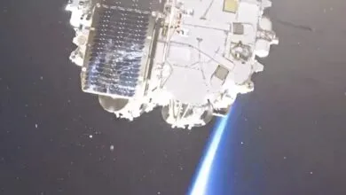 Close-up of a spacecraft against the dark expanse of space with Earth's glowing horizon below.