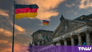 German flags wave proudly atop the historic Reichstag building in Berlin during a dramatic sunset.