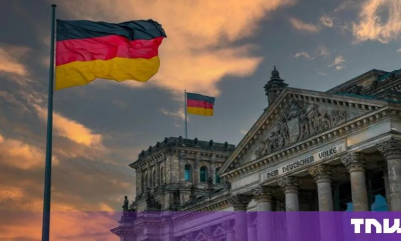 German flags wave proudly atop the historic Reichstag building in Berlin during a dramatic sunset.