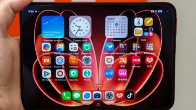 Close-up of a foldable smartphone held in hand, displaying the home screen with vibrant app icons and widgets.