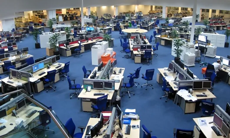 A bustling newsroom with numerous computer workstations arranged in rows, showcasing a dynamic and busy work environment.