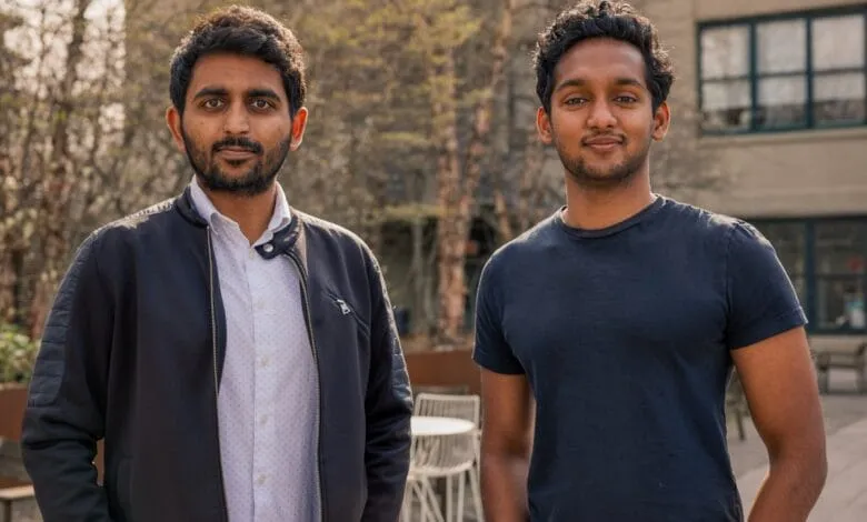 Two young men, co-founders of Nuvo, stand outdoors. One wears a dark jacket over a light shirt; the other wears a dark t-shirt.