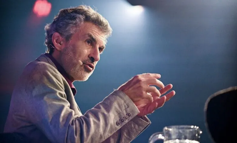 Yoshua Bengio gives a presentation, his hands gesturing animatedly. He's wearing a light gray jacket.