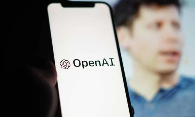 OpenAI logo displayed on a smartphone screen, with a blurred background of a person speaking.